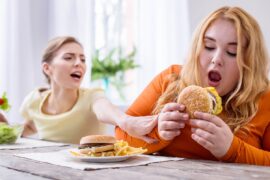gruba kobieta je hamburgera z frytkami